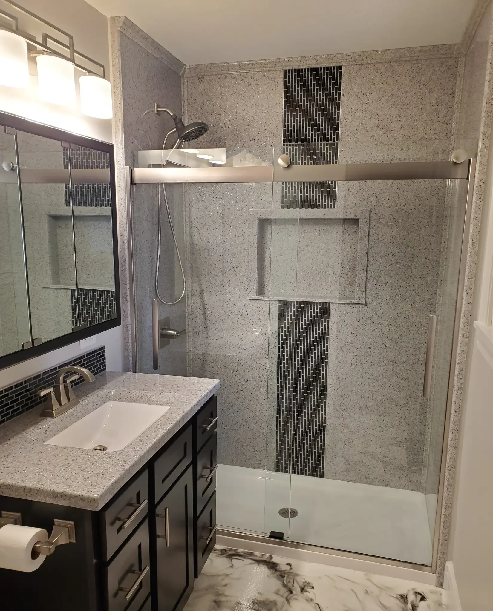 A bathroom with a glass shower door and sink.