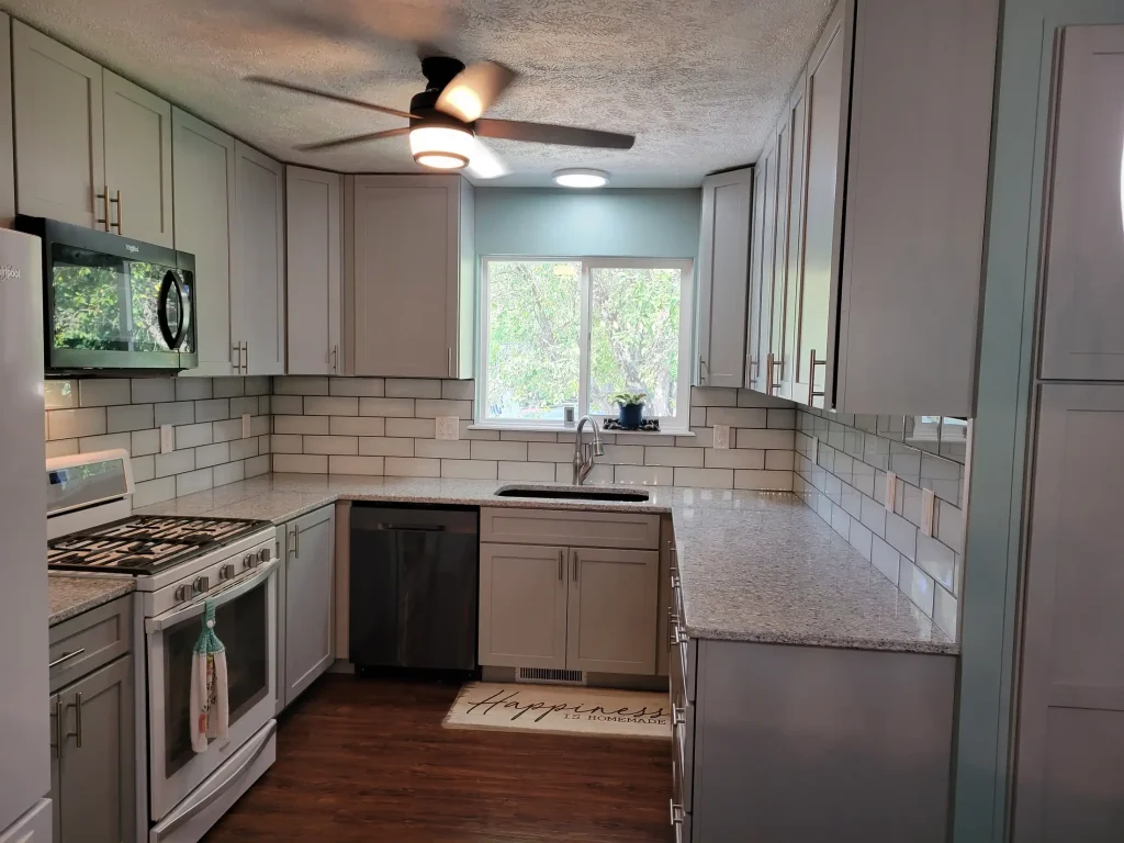 A kitchen with white cabinets and a ceiling fan.