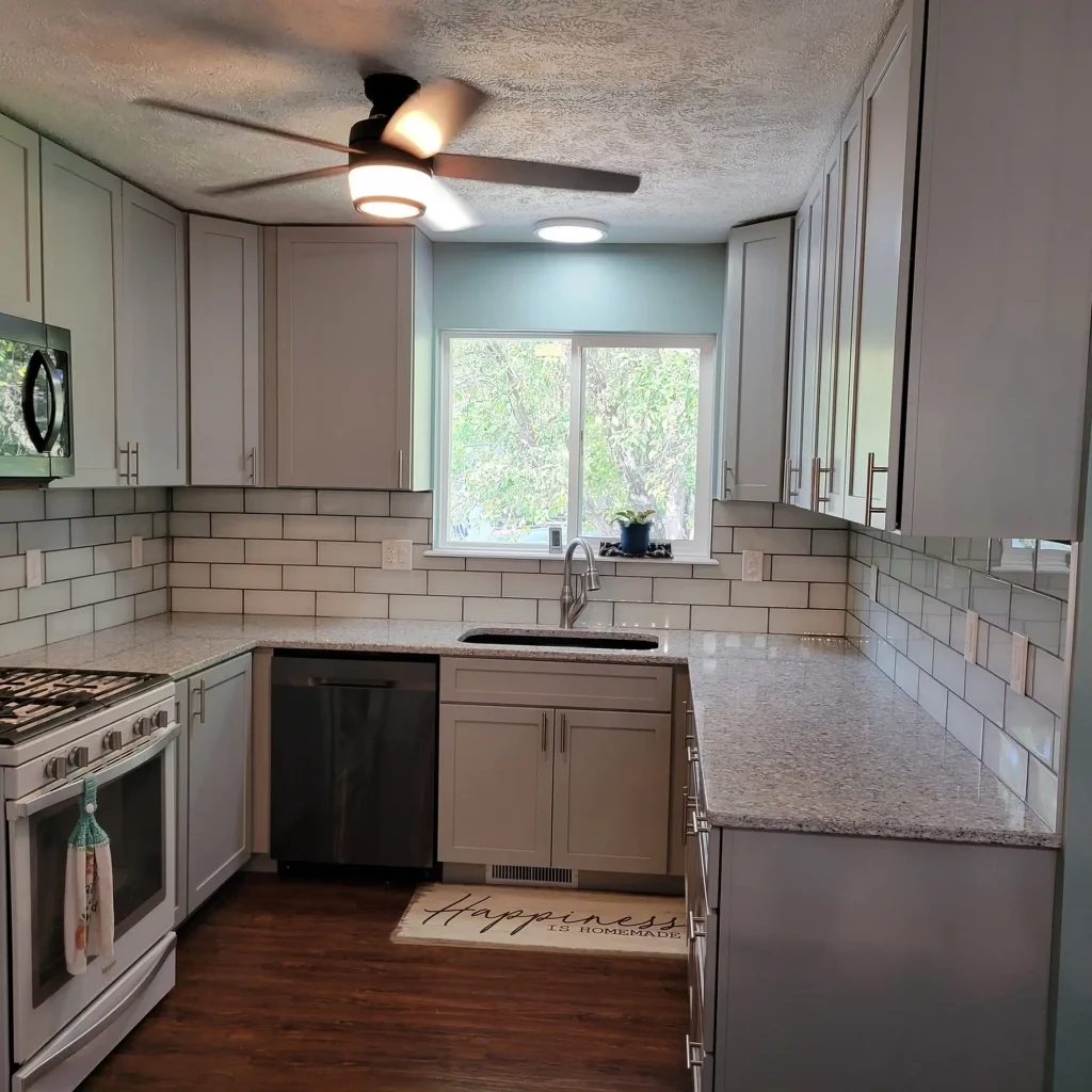 A kitchen with gray cabinets and a ceiling fan.