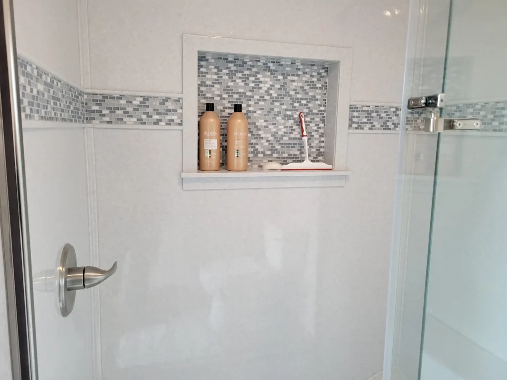 A bathroom with a glass shower door and shelves.