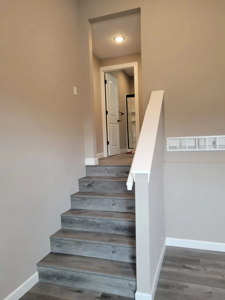 A staircase leading to a room with hardwood floors.