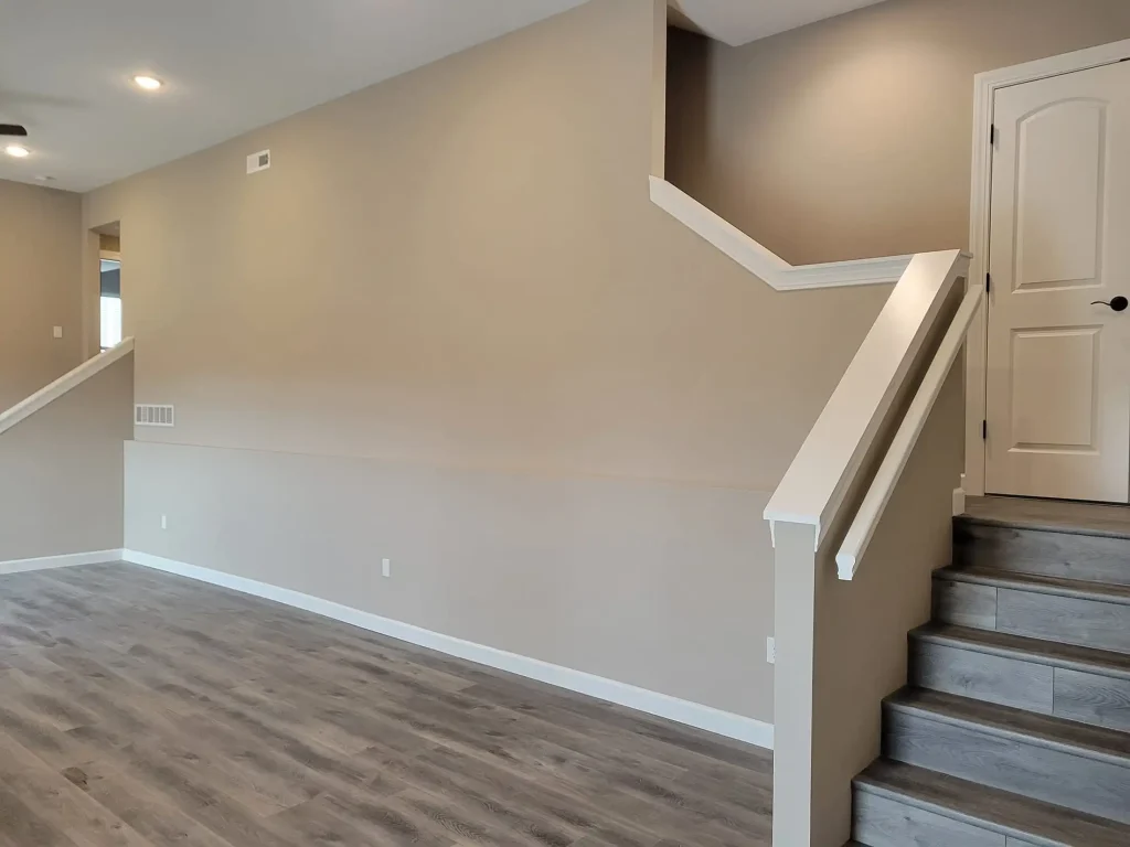 An empty living room with wood floors and stairs.