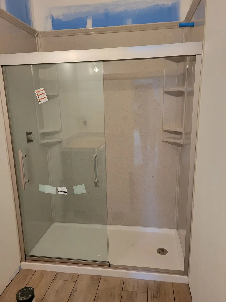 A glass shower door is being installed in a bathroom.