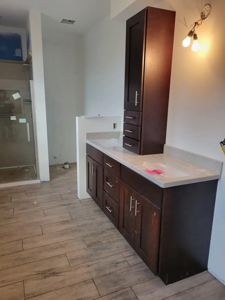 A bathroom with wooden cabinets and a shower.
