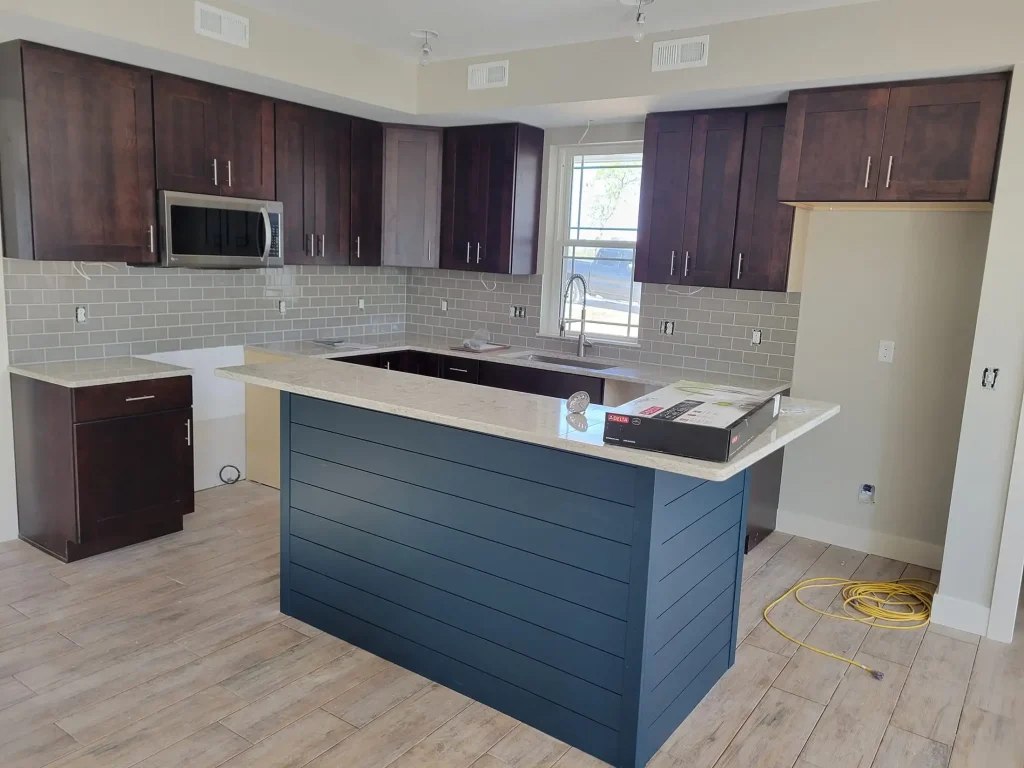 An empty kitchen with blue cabinets and hardwood floors.